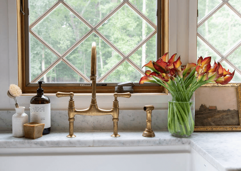 Farmhouse sink and gold faucet with vintage print next to the sink