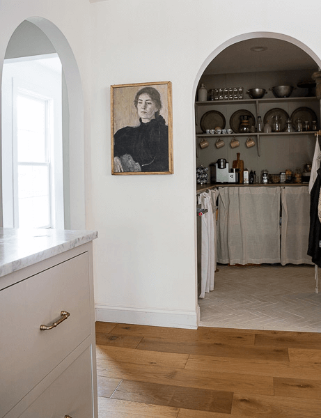 Arched entrance to butler's pantry with vintage charcoal painting on the wall