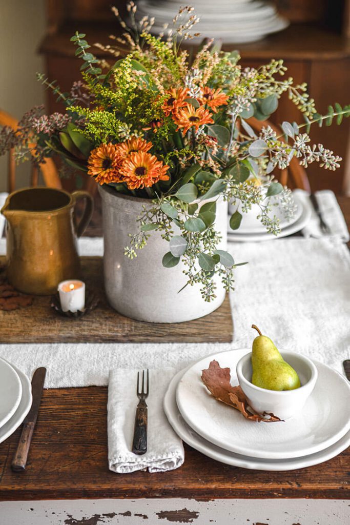 Table setting with a pear and orange flowers in a centerpiece