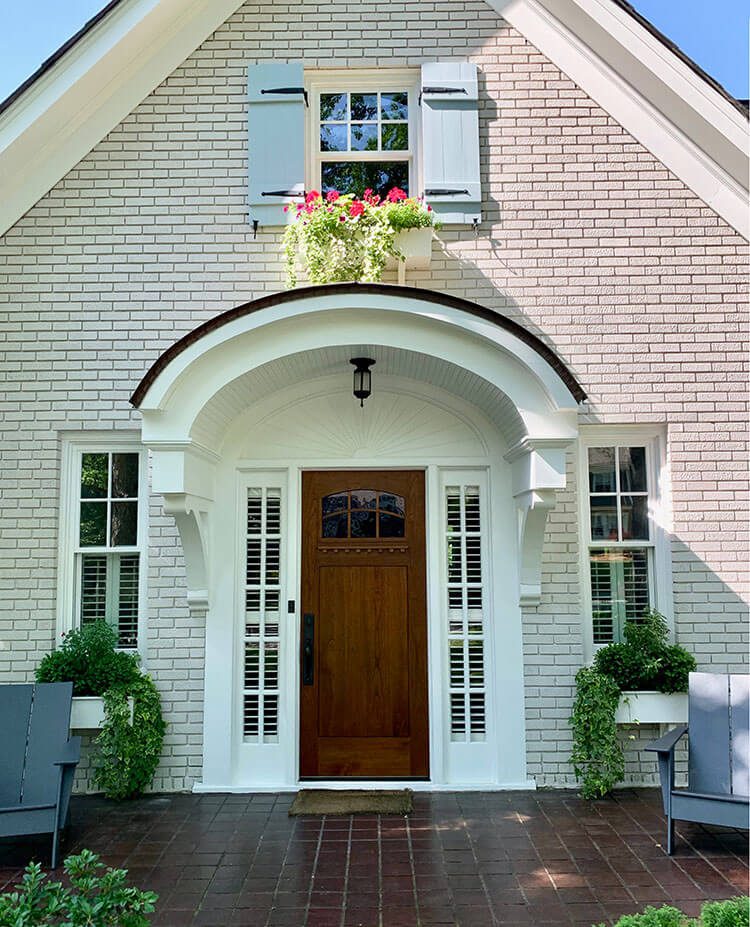 Front door with brick siding, arched portico and window box to help pick doors
