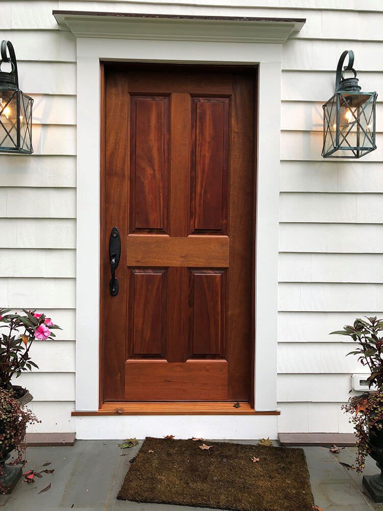 Front door dark wood against white home siding to pick doors