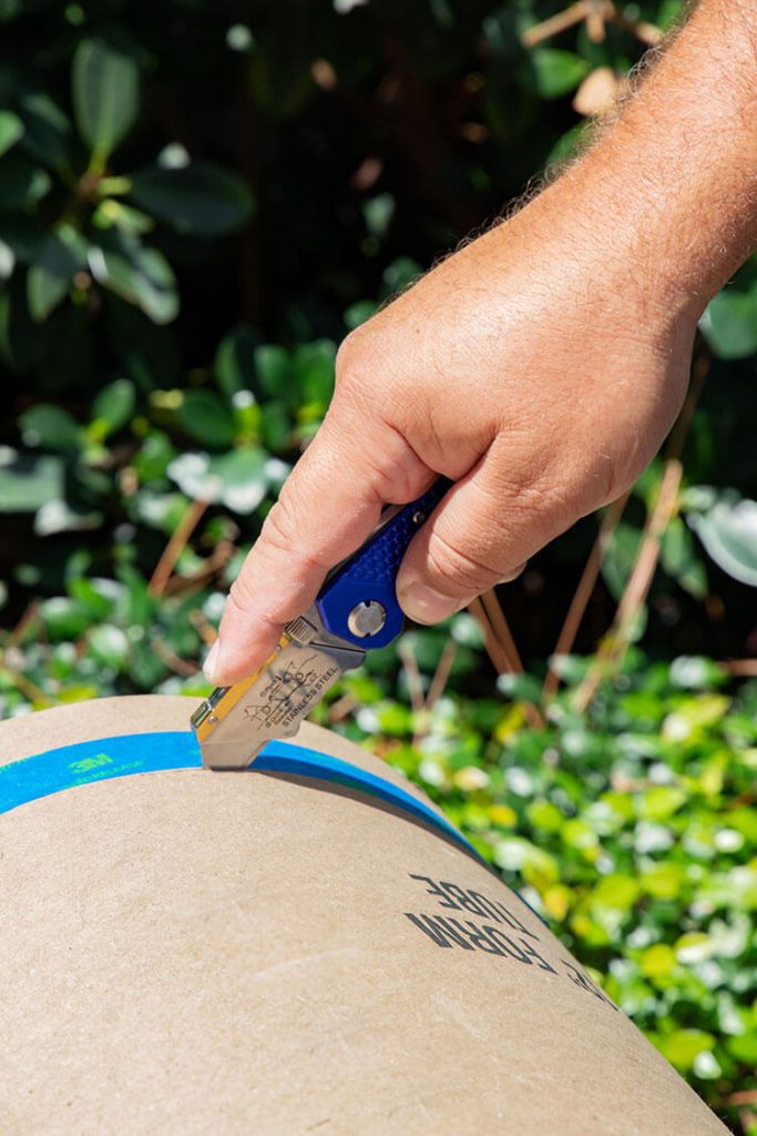 Man cutting tube with painter's tape around it