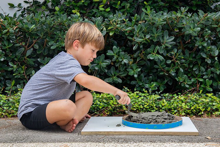 Little boy smoothing DIY concrete chargers