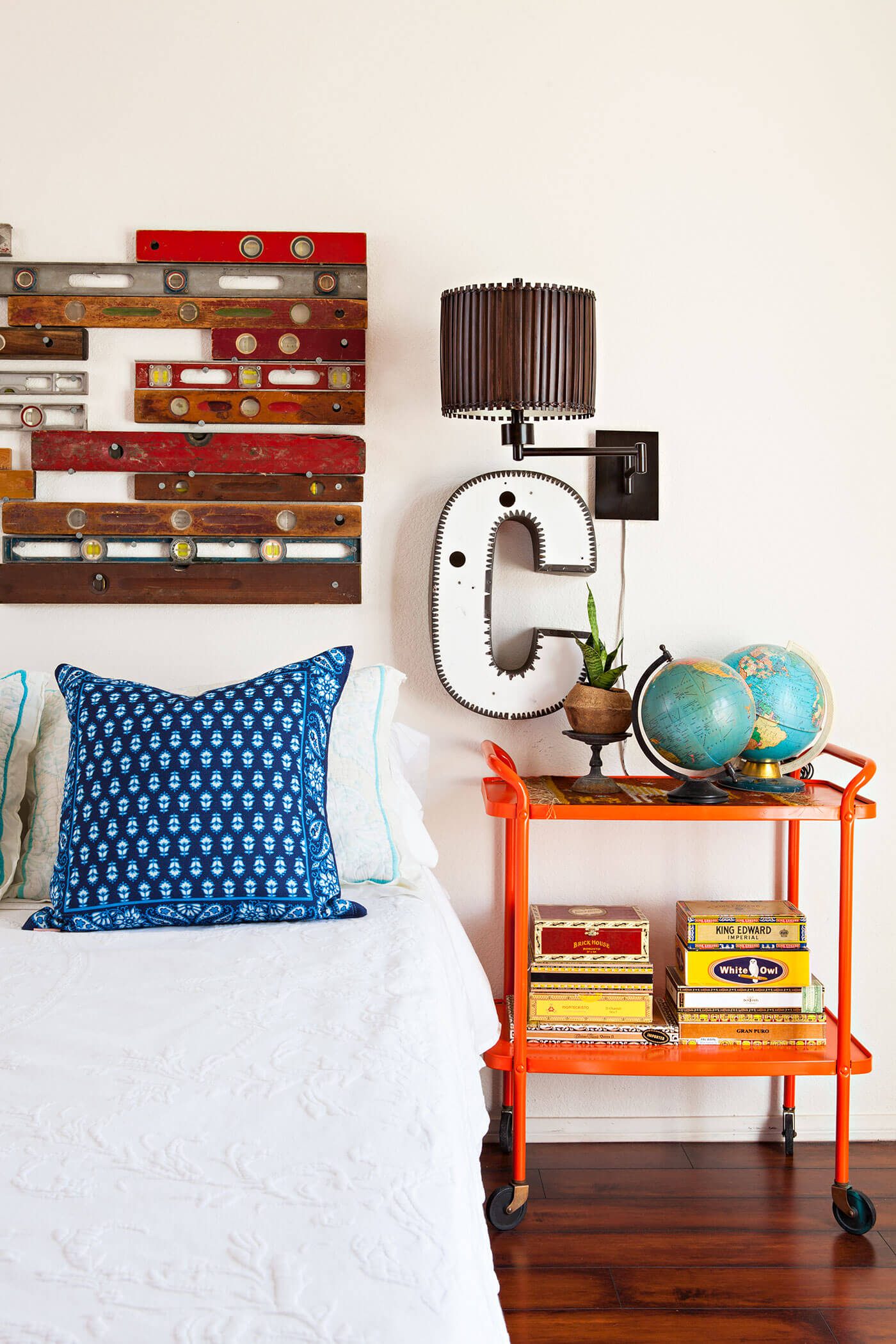 Bedroom with old bar cart as nightstand and vintage levels as headboard