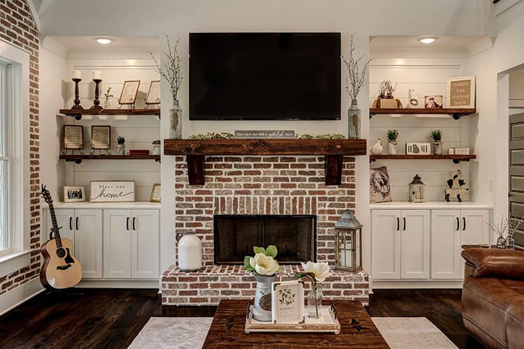 Living room with TV mounted on the wall, and brick hearth above fireplace
