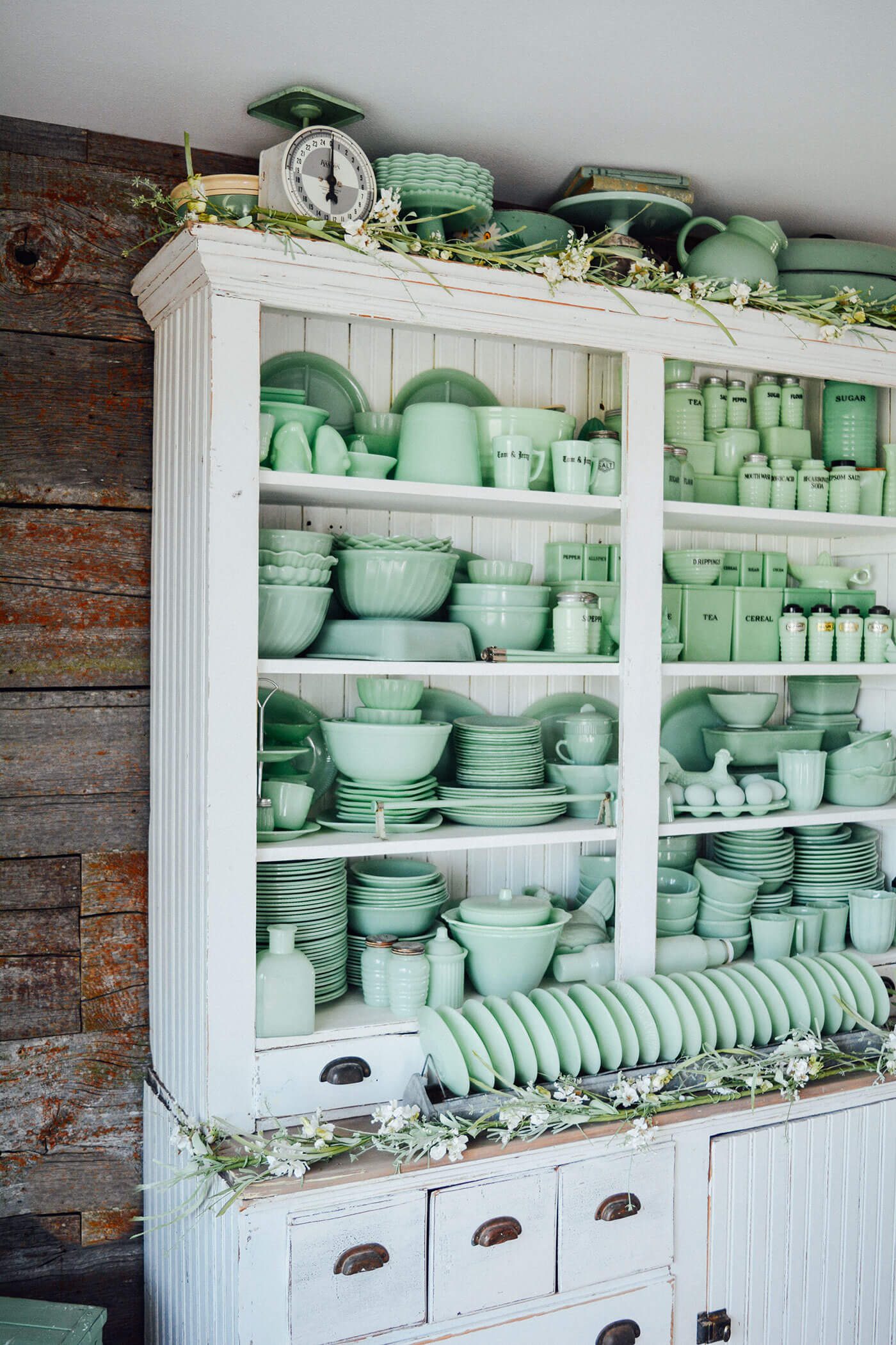 White cupboard full of green Jaedite dishware