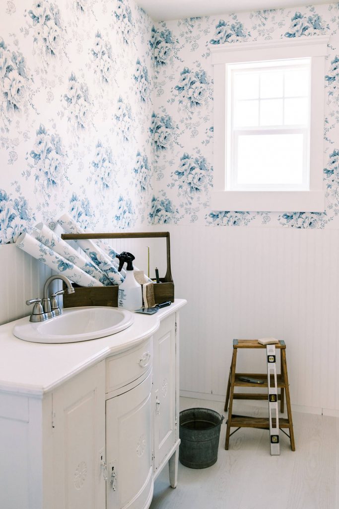 Blue and white bathroom with supplies to install wallpaper
