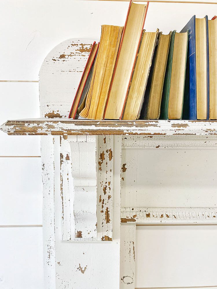 close up of mantel with flaking paint and books on top