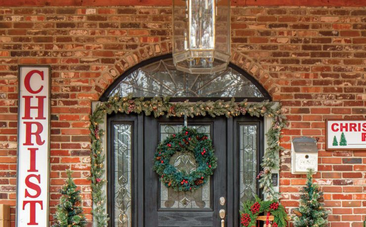 Front door with Christmas garland and sign art and Christmas decor