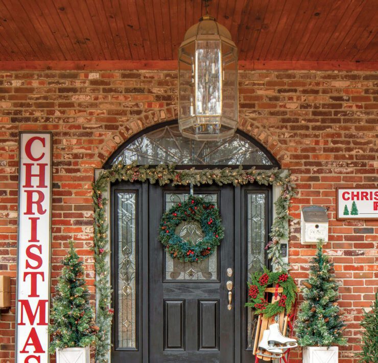 Front door with Christmas garland and sign art and Christmas decor