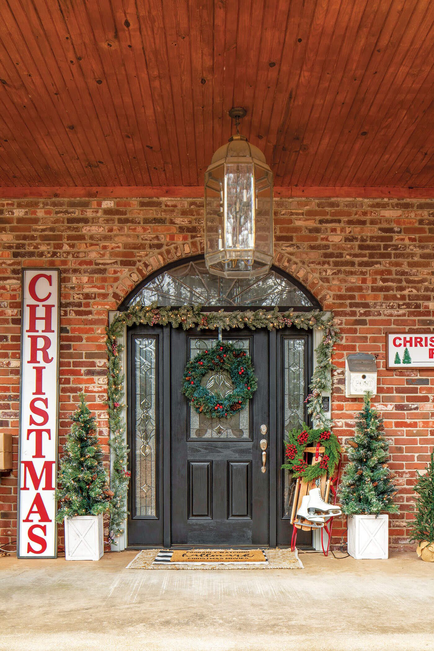 Front door with Christmas garland and sign art and Christmas decor