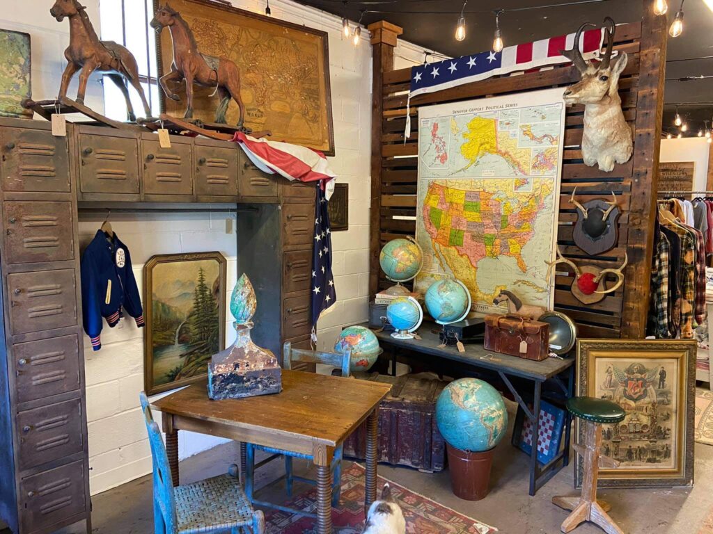 Corner of antiques shops with vintage globes, lockers, and hanging antlers