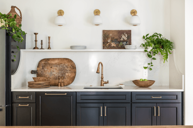 Kitchen sink with black cabinets and white walls with open shelves