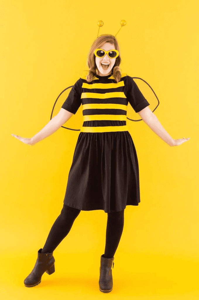 Girl with bumble bee costume against yellow backdrop