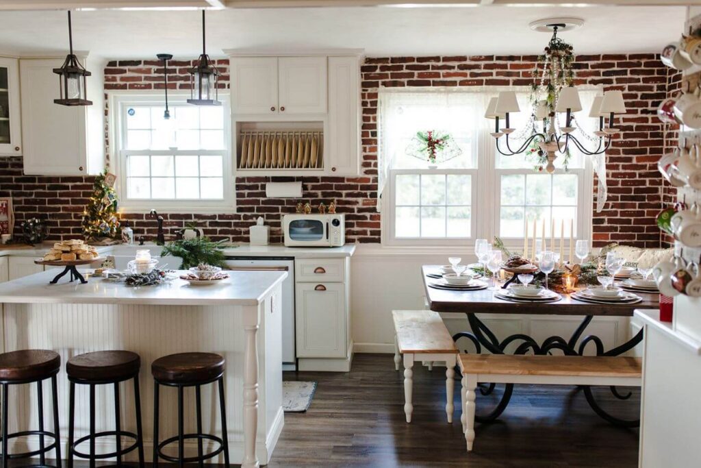 This Pennsylvania Christmas home has a red brick kitchen that is perrfect for a traditional Christmas color palette. White cabinets and evergreen accents complete the look.