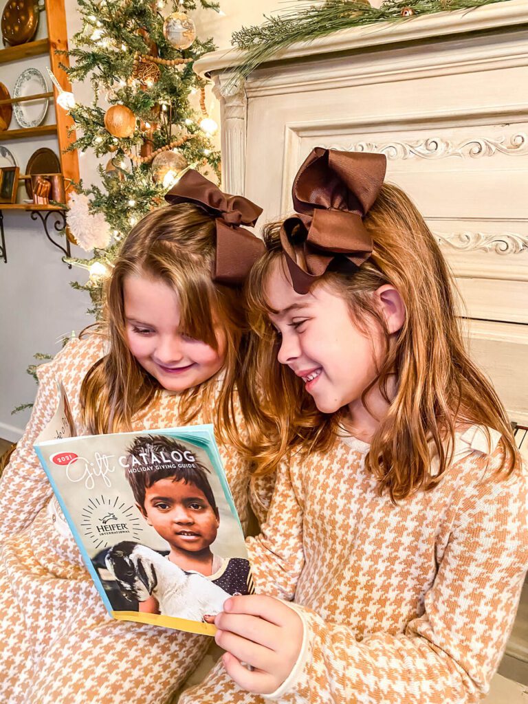 Two young girls in matching dresses, looking at Heifer International catalog