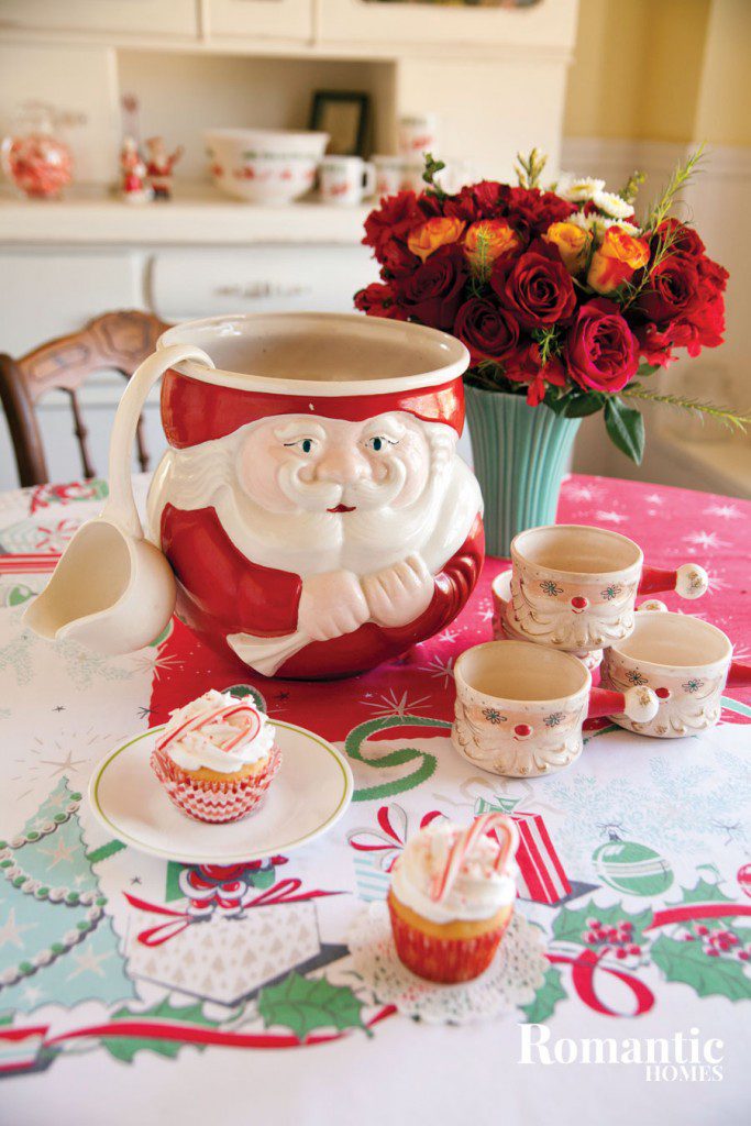 festive holiday tablescape with a santa claus cookie jar in the center surrounded by santa mugs and cupcakes
