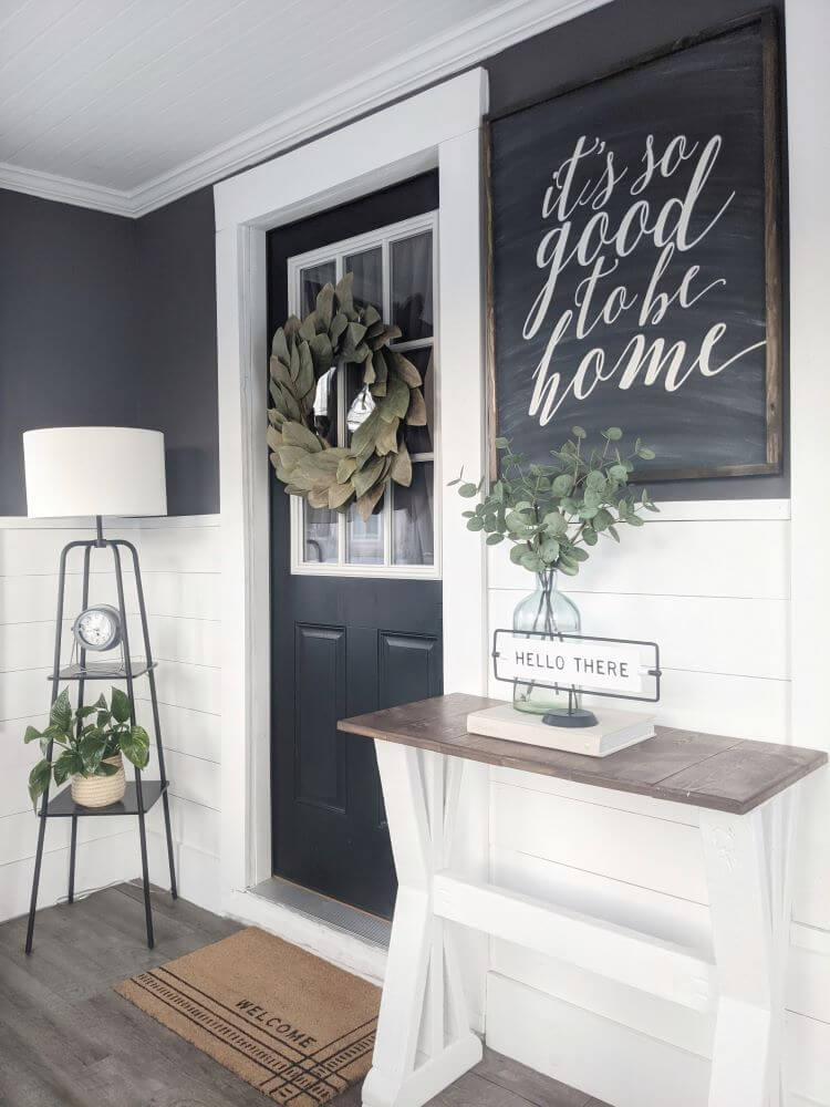 The home's front door is painted black to offset the shiplap style trim on either side of the door