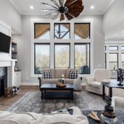 A large one-plan living room and dining area with white walls and black frame windows. The furniture is also painted a dark black to match the white farmhouse's black and white color scheme.