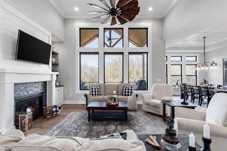 A large one-plan living room and dining area with white walls and black frame windows. The furniture is also painted a dark black to match the white farmhouse's black and white color scheme.