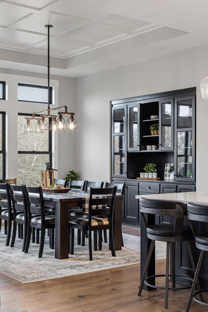 The dining room chairs come in a checkered black and white pattern to fit the large black built-in cabinetry sitting beside the table.