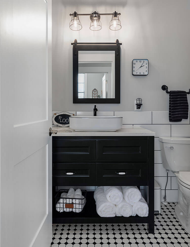 Oversized white subway style tile is grouted black to complete the look of this mostly white farmhouse kitchen.