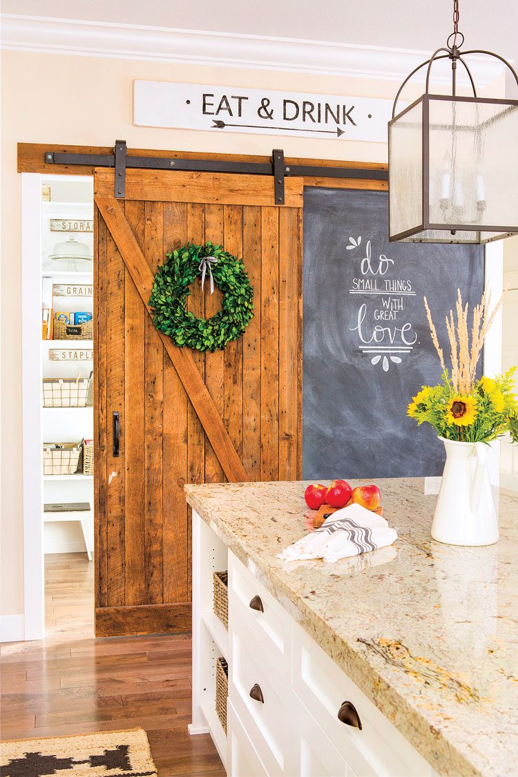 A white farmhouse kitchen with poured concrete countertops and white shiplap beside two large pendant lights