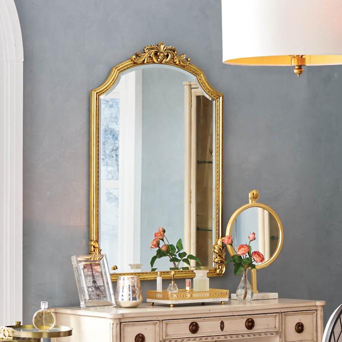 Gold mirror on wall with vanity in front