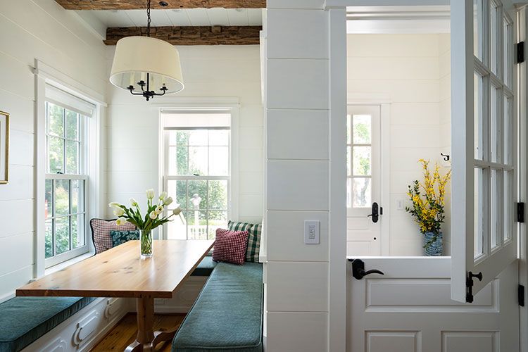 The Great Room's breakfast nook has a farmhouse style wood table and blue bench cushions