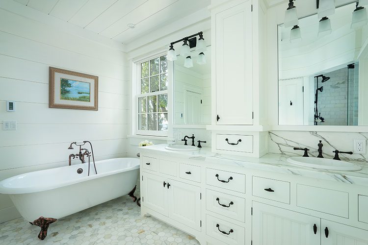 The mostly white master bathroom is dotted with dark hardware to offer pops of black against the white