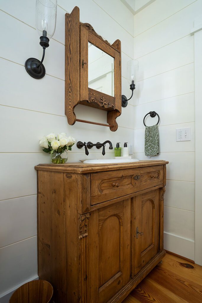 A pine dresser with carved accents was retrofitted into a vanity for the powder room for this farmhouse refresh