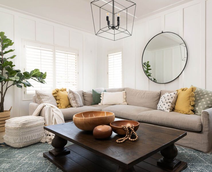 Living room with yellow pillows, gray sofa and wall paneling for boho farmhouse style.