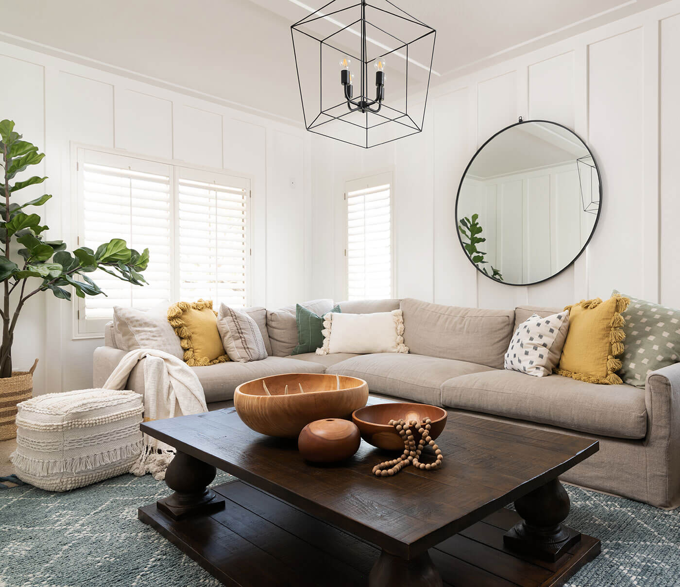 Living room with yellow pillows, gray sofa and wall paneling for boho farmhouse style.