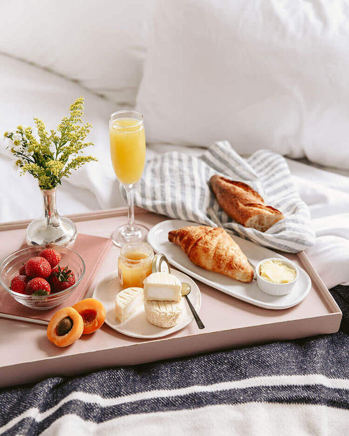 Style your home like a pro with breakfast in bed with orange juice and croissants
