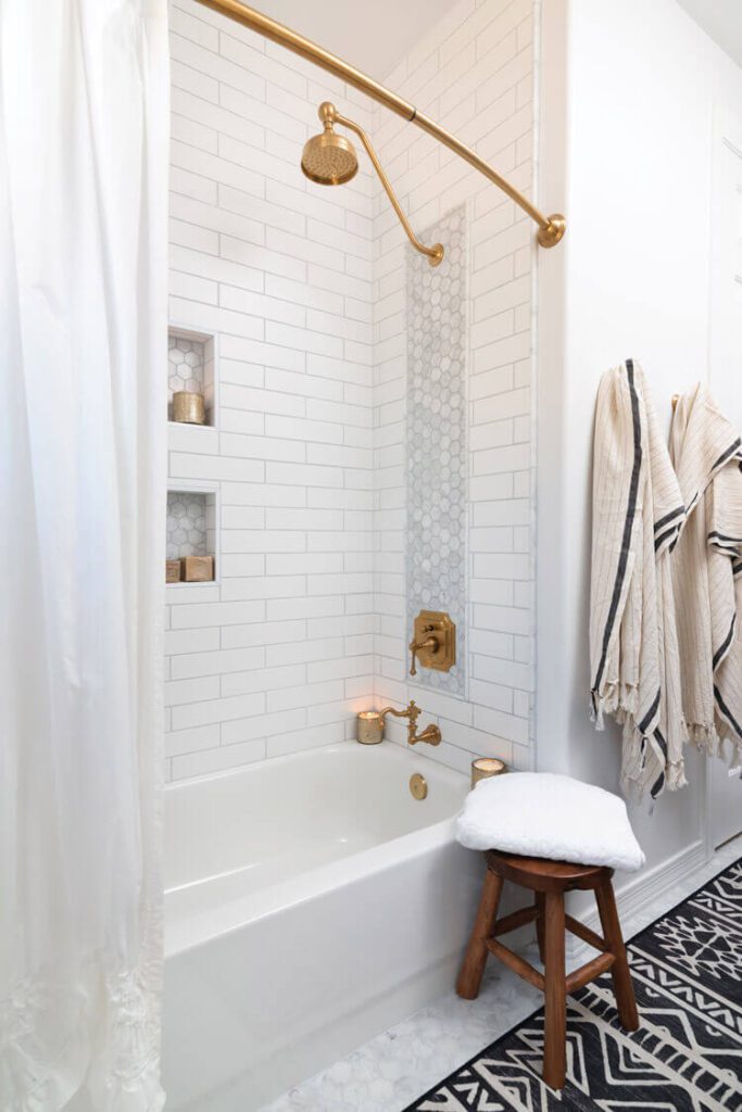 This bathroom has a titled shower with a hexagon pattern and gold hardware.