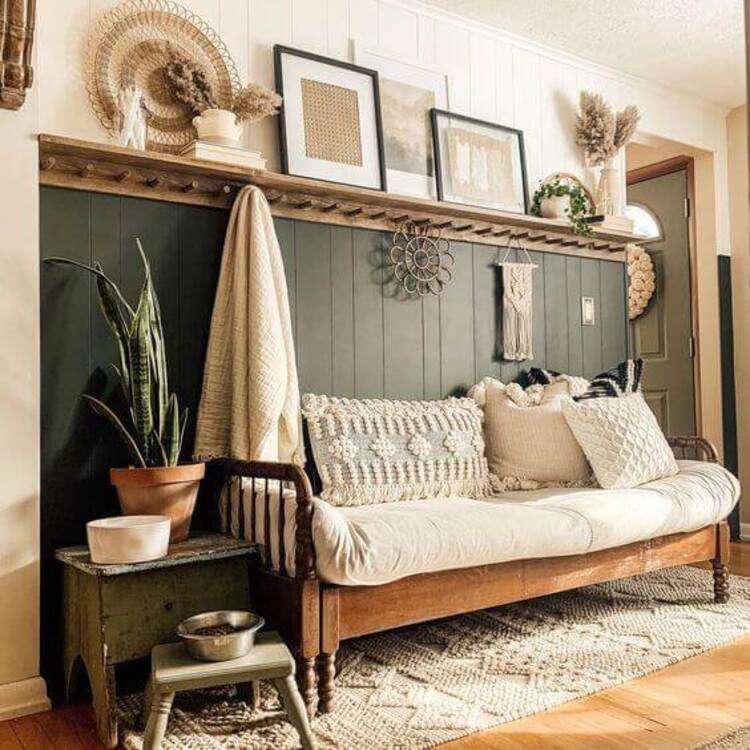 An old wooden bench in the entryway holds neutral throw pillows with a peg rack above.