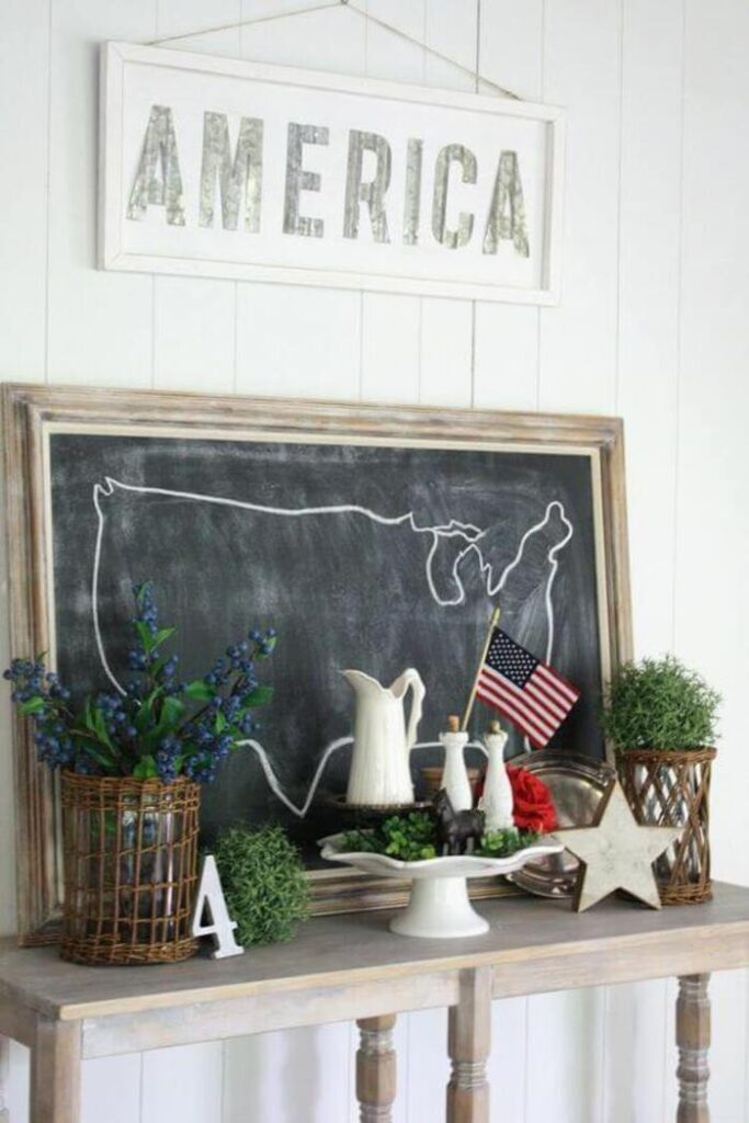 Chalkboard with United States line art on a shelf with other 4th of July décor.