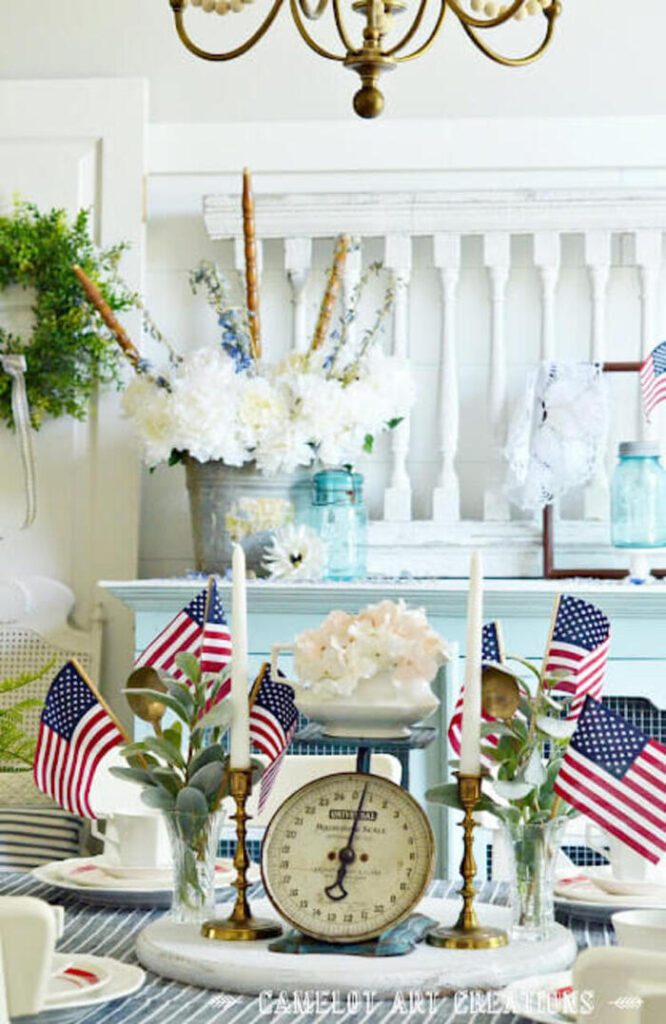 4th of July décor centerpiece with candlesticks, vintage weight, and mini flags.