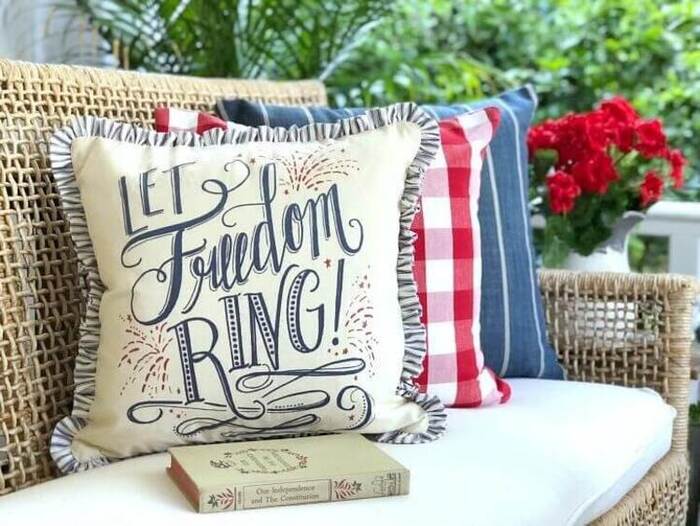4th of July "Let Freedom Ring" throw pillows on an outdoor bench.
