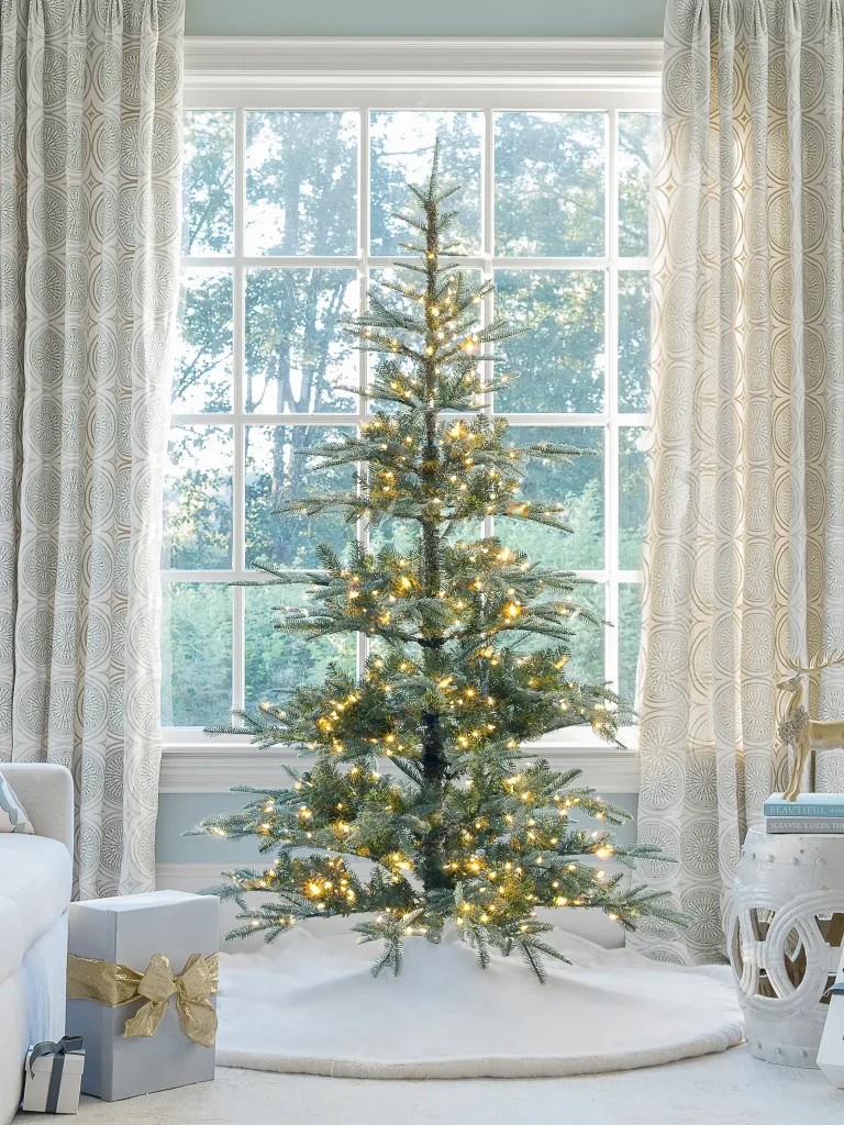 Noble fir lit artificial Christmas tree next to a window, for festive farmhouse wish list