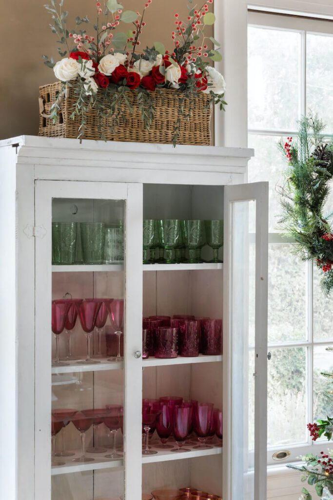 white china cabinet with red and green glassware