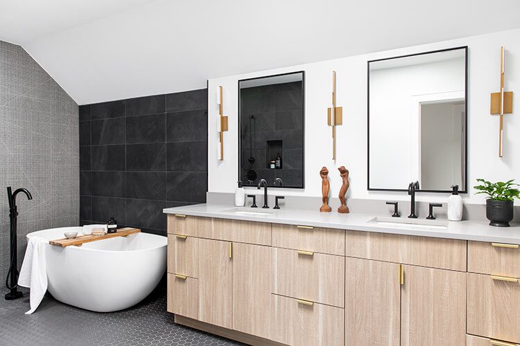 Large black tile acts as an accent wall framing the white tub.