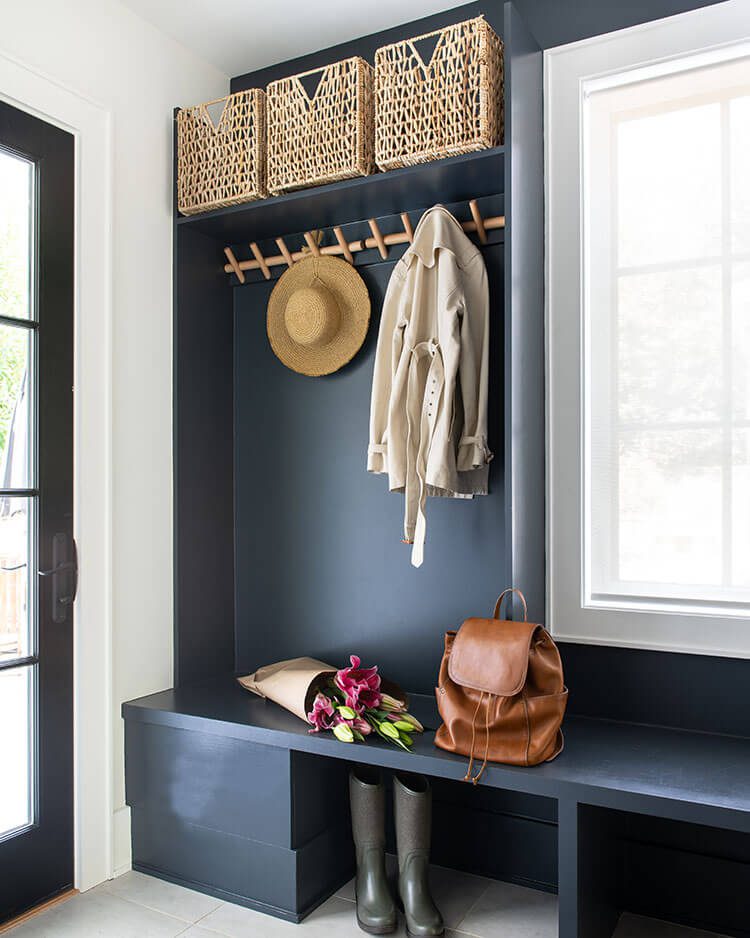 The mudroom has a bold back color meant to offset the white walls of the global farmhouse style home.