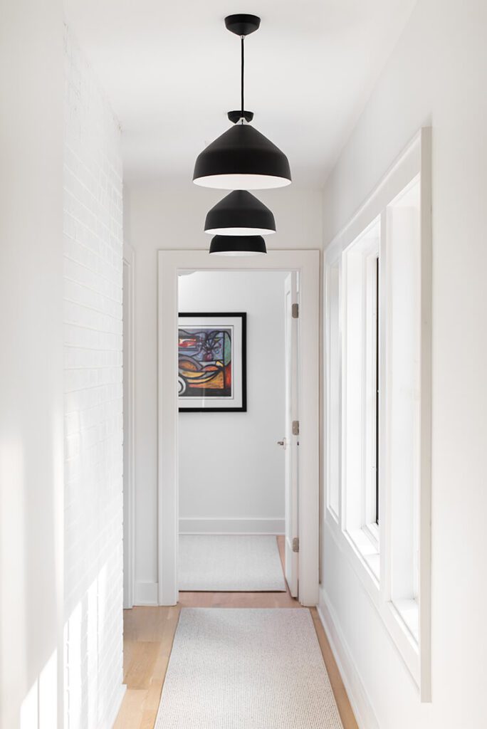 Hanging black lamps dangle over oak wood floors and crisp white walls.