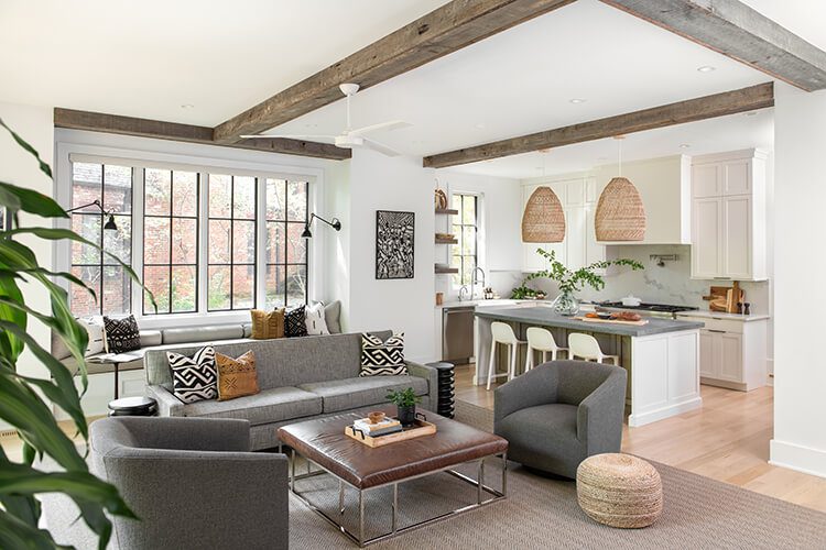 Aged wood beams sit on a white ceiling above a gray couch.