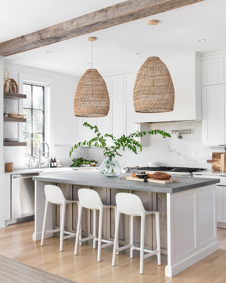 Large light fixtures made to look like baskets hang over a gray kitchen countertop in the global farmhouse style home.