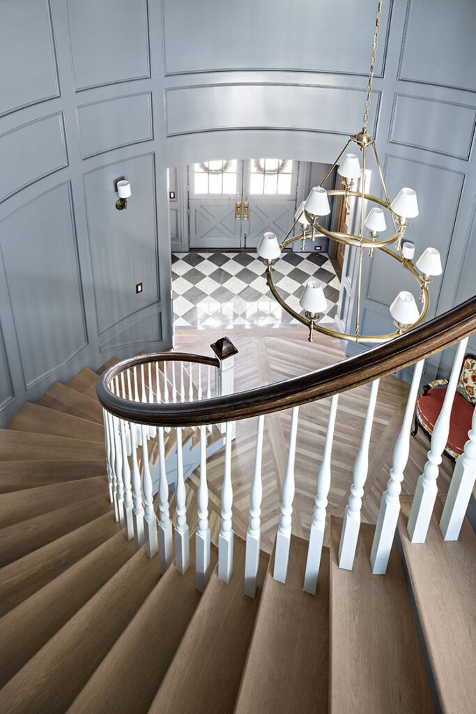 Spiral staircase with blue-gray walls and wall paneling