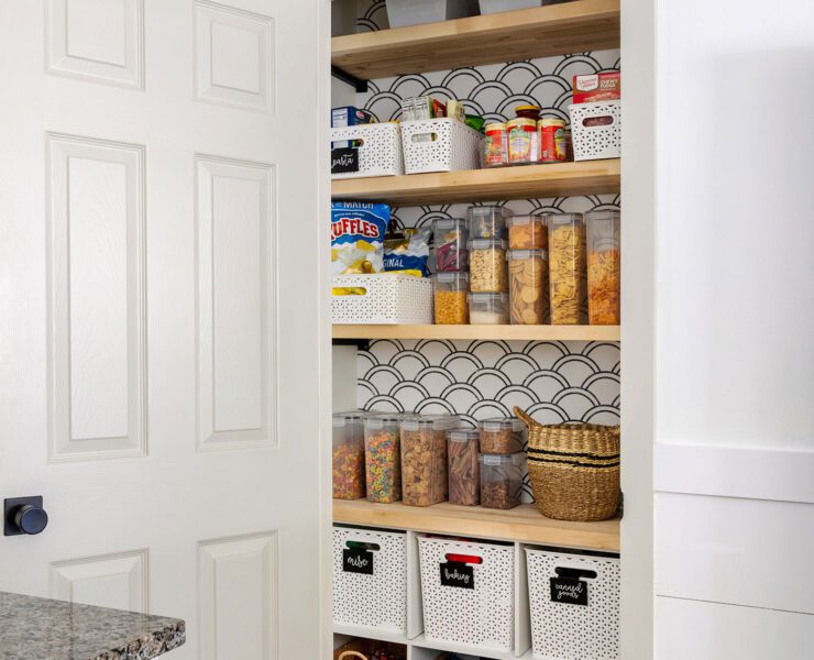 Open pantry door with wallpaper behind shelves and organized food