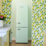 Wallpapered wall with archway entrance and retro fridge through archway