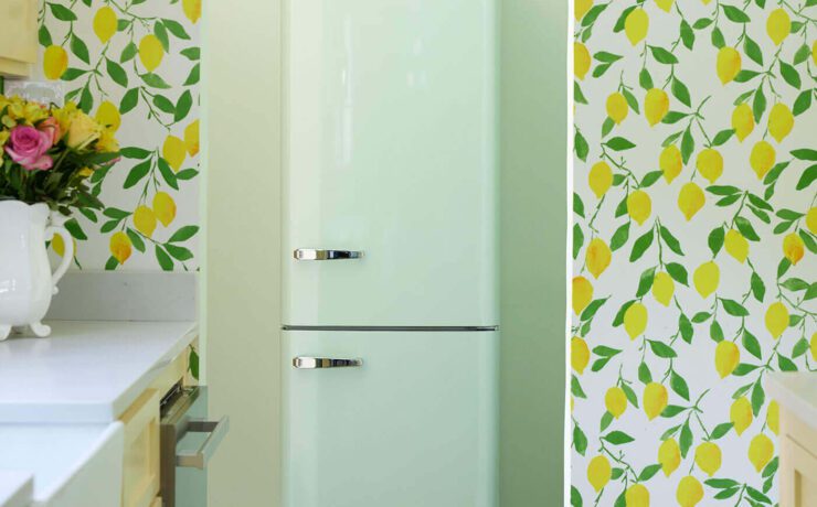Wallpapered wall with archway entrance and retro fridge through archway